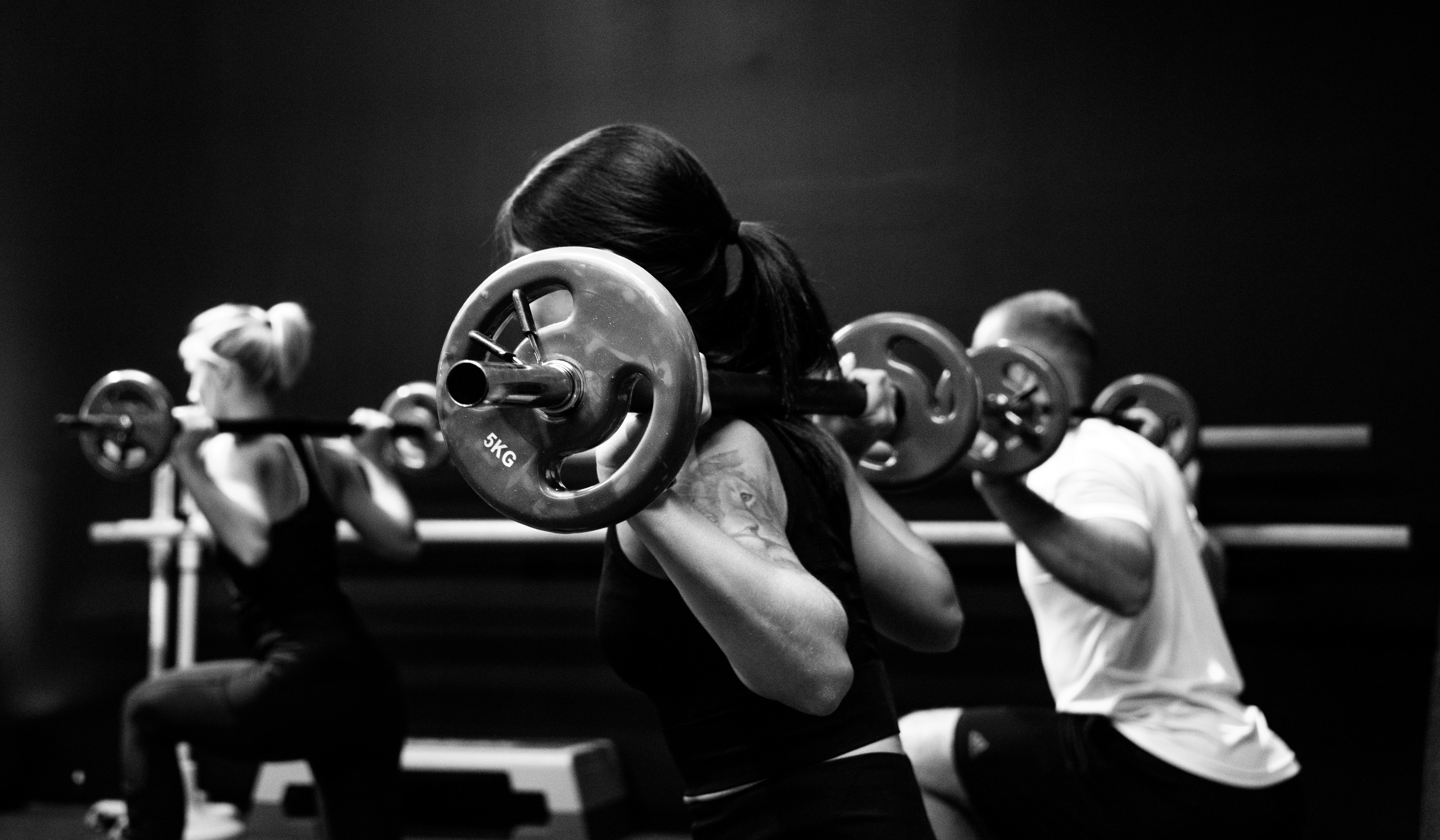 three person lifting barbels